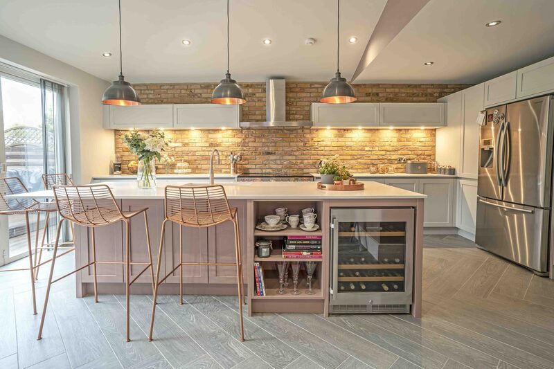 Contemporary kitchen featuring rear brick slip wall and rose gold furnishings