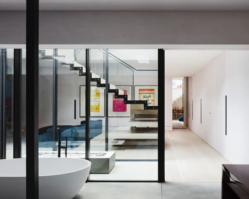 Steel framed internal glass partition separating freestanding bath and hallway