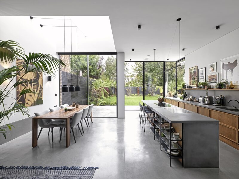 Open plan kitchen with large elevations of glazing, natural textures and house plants creating a biophilic design