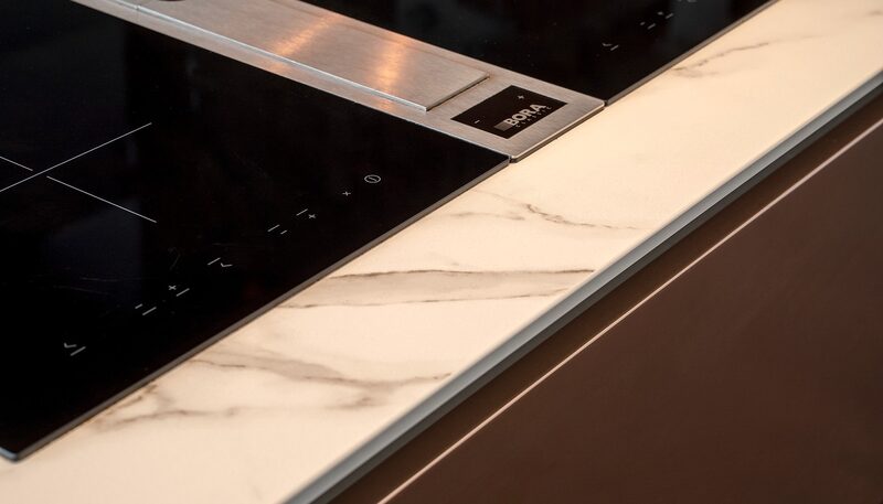 Porcelain vs quartz worktops: BORA hob and integrated extractor set into a pale veined worktop in a Watermark kitchen.