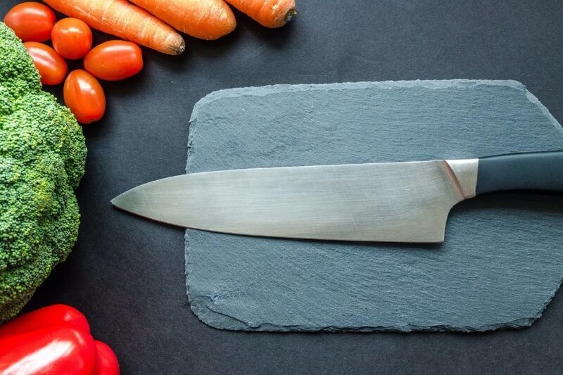 kitchen knife and cutting board on a dark kitchen counter
