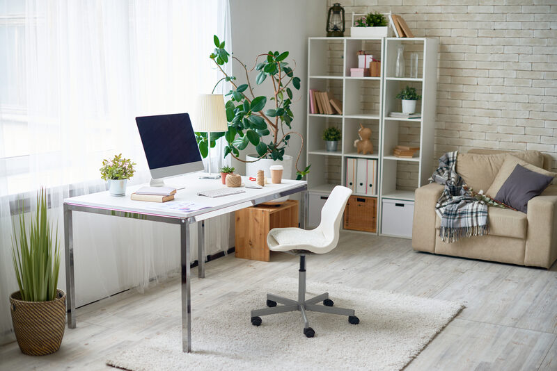 Home office with pale colour scheme, houseplants and a large window above desk