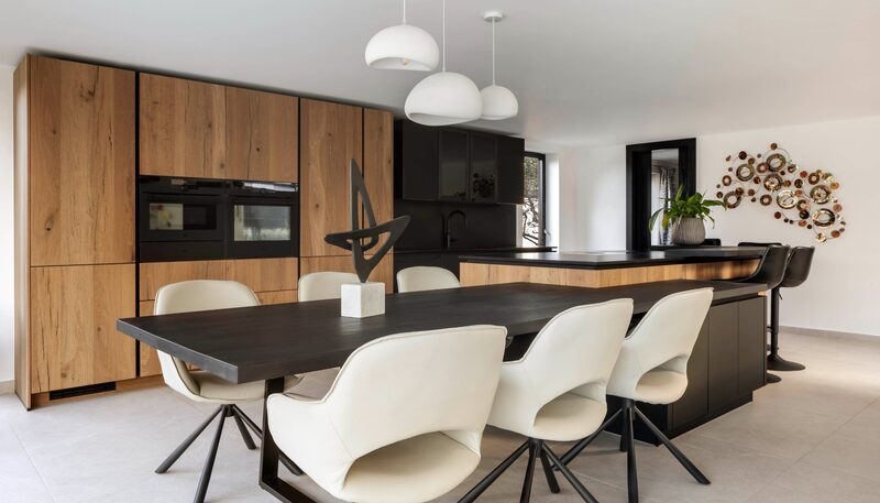 Porcelain vs quartz worktops: Dairy Farm kitchen by Watermark Kitchens with navy cabinetry, a pale island worktop and tan bar stools.