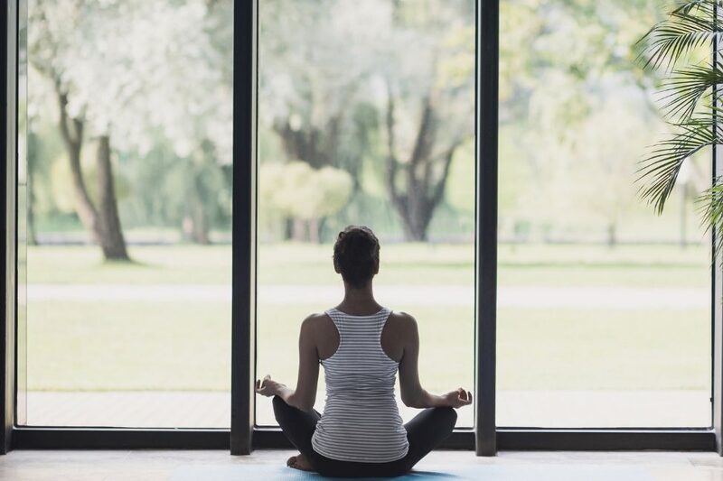 woman doing yoga in highly glazed studio space