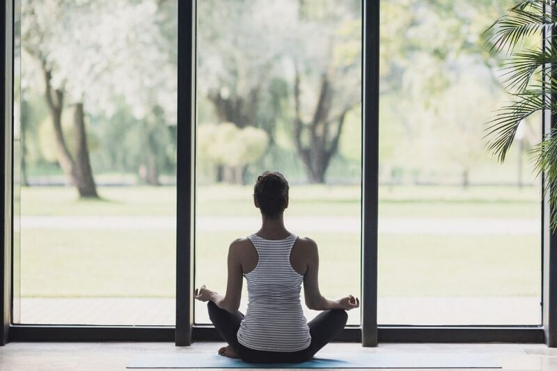 woman doing yoga next to floor-to-ceiling glazing